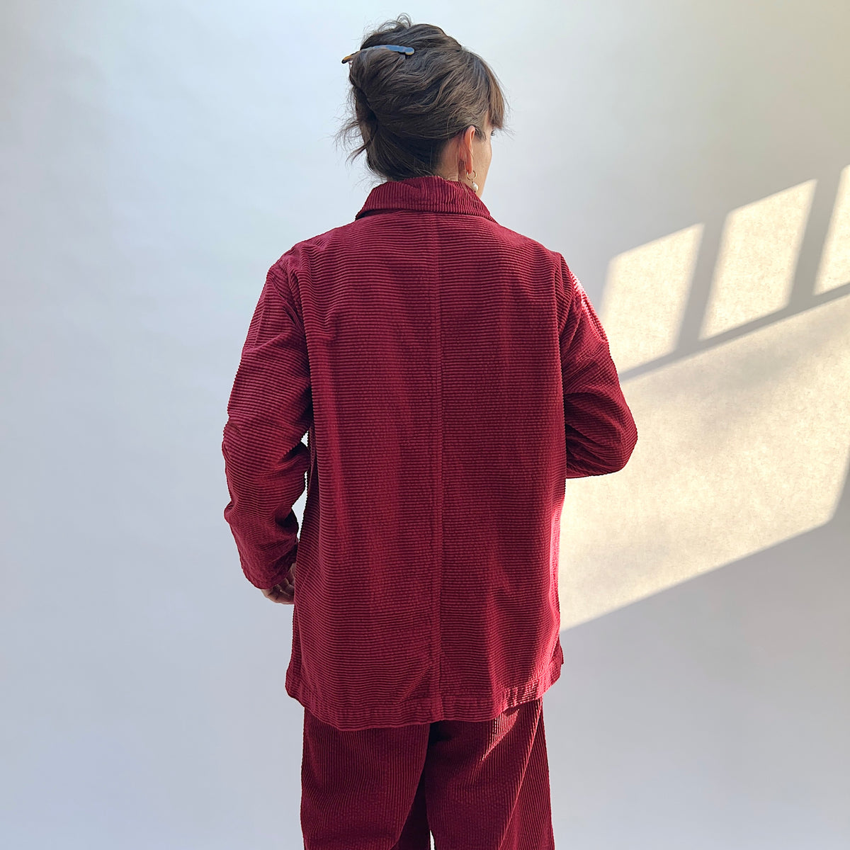 Back view of the Lux Corduroy Long Blazer in Maraschino on a model, showing the horizontal corduroy texture and center-back seam.
