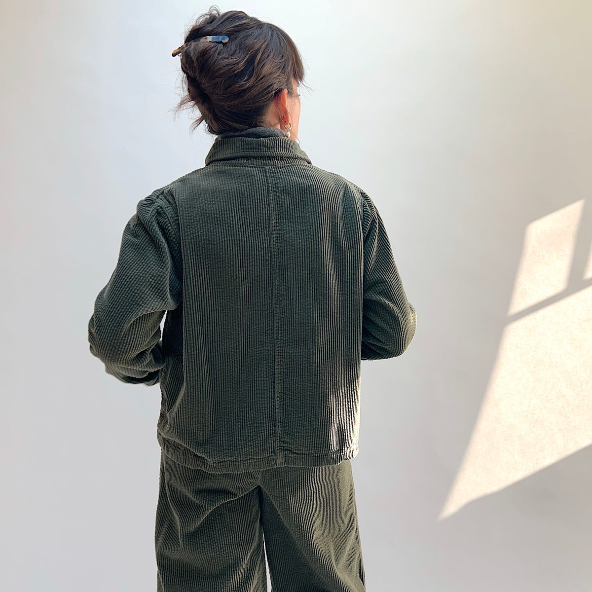 Back view of the Lux Corduroy Cropped Jacket in Kelp on a model, showing the vertical corduroy texture and center-back seam.
