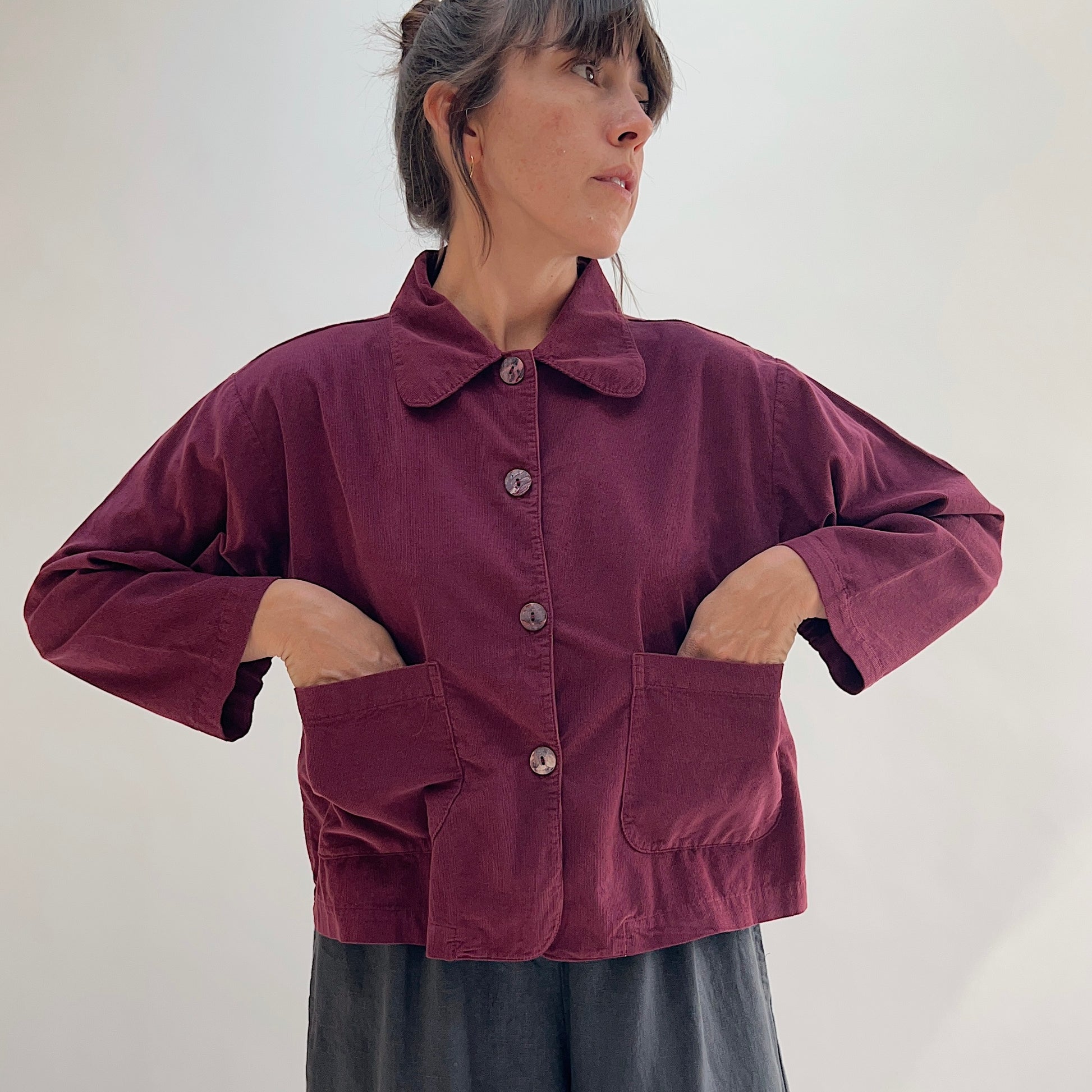 Back view of the Bryn Walker Corduroy Audrey Jacket in Black, showing cropped hemline, relaxed silhouette, and pinwheel corduroy texture, paired with black trousers
