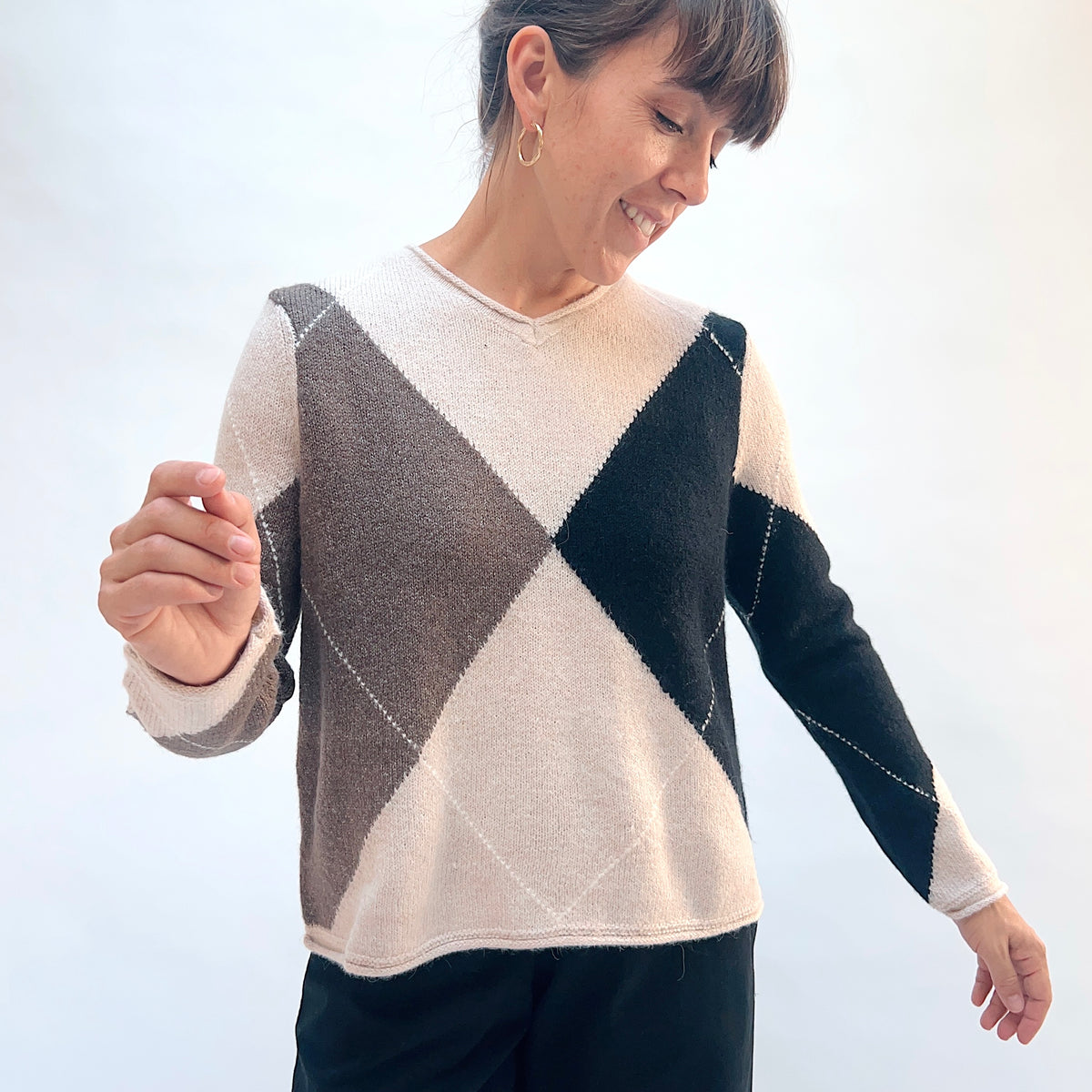 Habitat Alpine Argyle Pullover in Dove, front three-quarter view showing the V-neckline, argyle pattern, and curved hem
