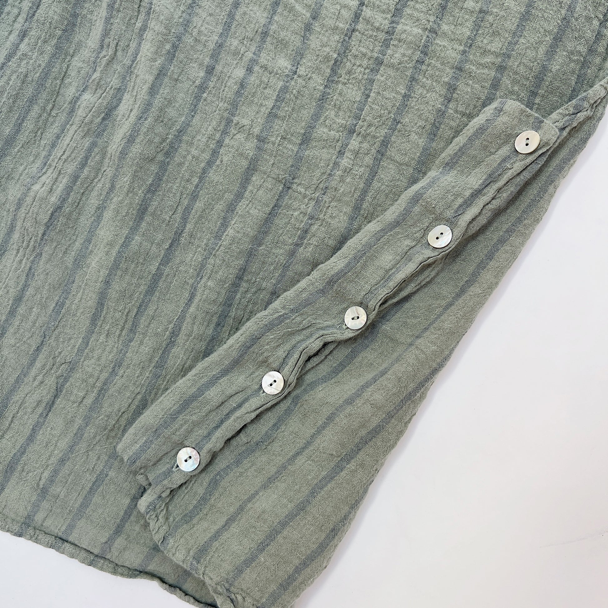 Close-up detail of five white buttons along the side seam of the Cut Loose Striped Side Button Shell Tank in Balsam Green, 100% linen
