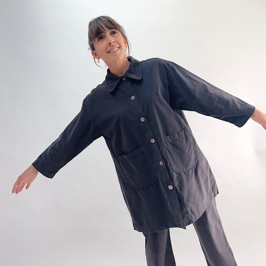 Model with arms outstretched wearing the Bryn Walker Corduroy Car Coat in Fig, front view showing rounded point collar, mother of pearl buttons, two large front patch pockets, 3/4 sleeves, and deep fig pinwheel corduroy, styled with matching corduroy pants
