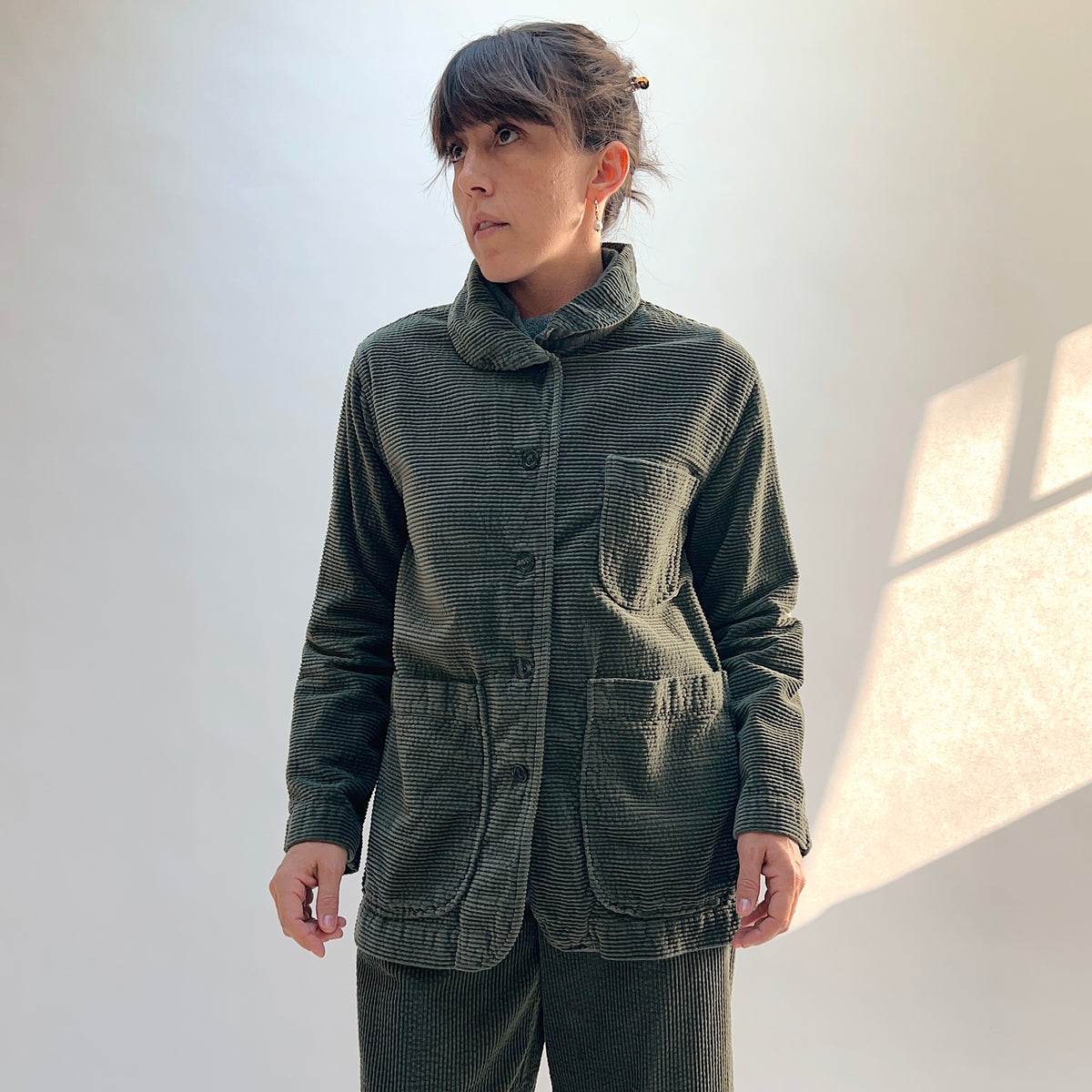 Front view of the Lux Corduroy Long Blazer in Kelp on a model, showing the folded collar, chest pocket, and two lower patch pockets.

