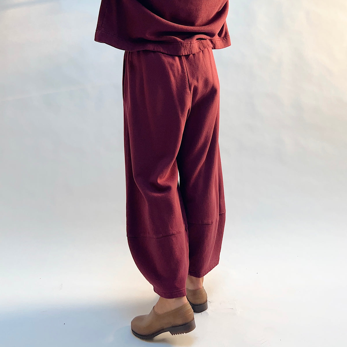 Angled back view of Oliver Fleece Pant in Rhone, showing the rounded legs and horizontal lower-leg seams.
