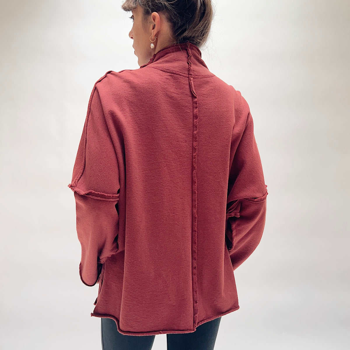 Back view of the Eleven Stitch Long Rib Out Funnel Neck Slub Sweatshirt in Berry, showing the exposed raw rib center back seam running the full length, raw rib seams at the shoulder and sleeve seams, drop shoulders, and raw-edge curved hem in deep berry slub cotton
