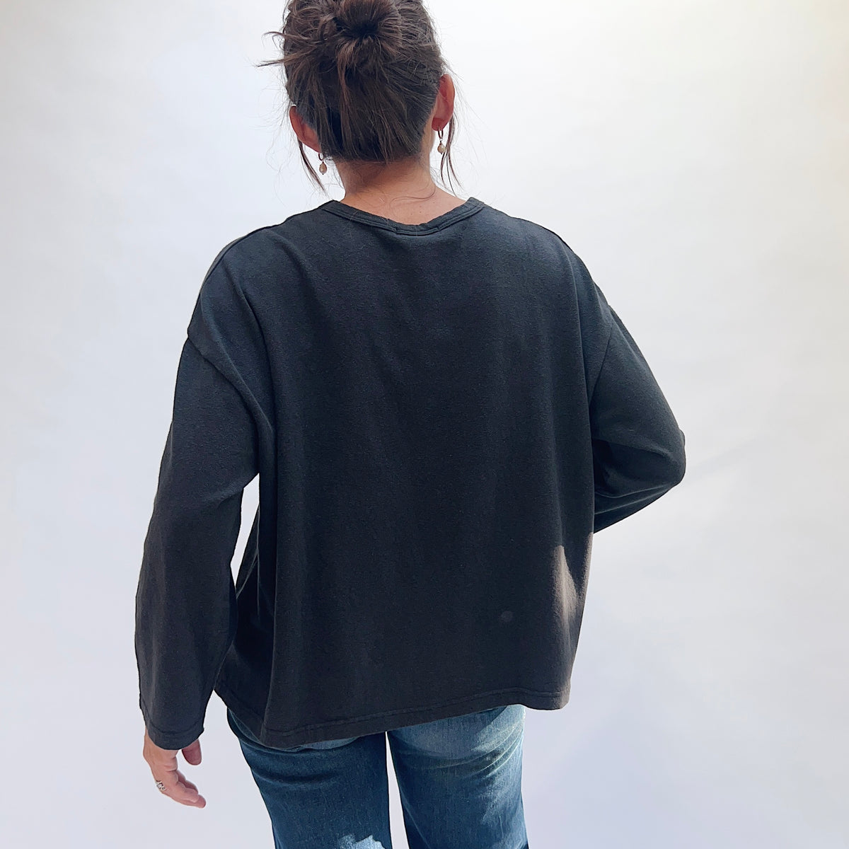 Back view of a model wearing the black cotton knit pullover, showing the plain back and dropped shoulders.
