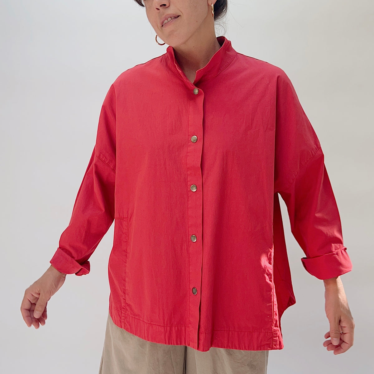 Eleven Stitch Stand Collar Jacket in Cayenne, front view on model, showing stand collar, five metal snap closures, two front patch pockets, and relaxed boxy silhouette, paired with khaki wide-leg trousers
