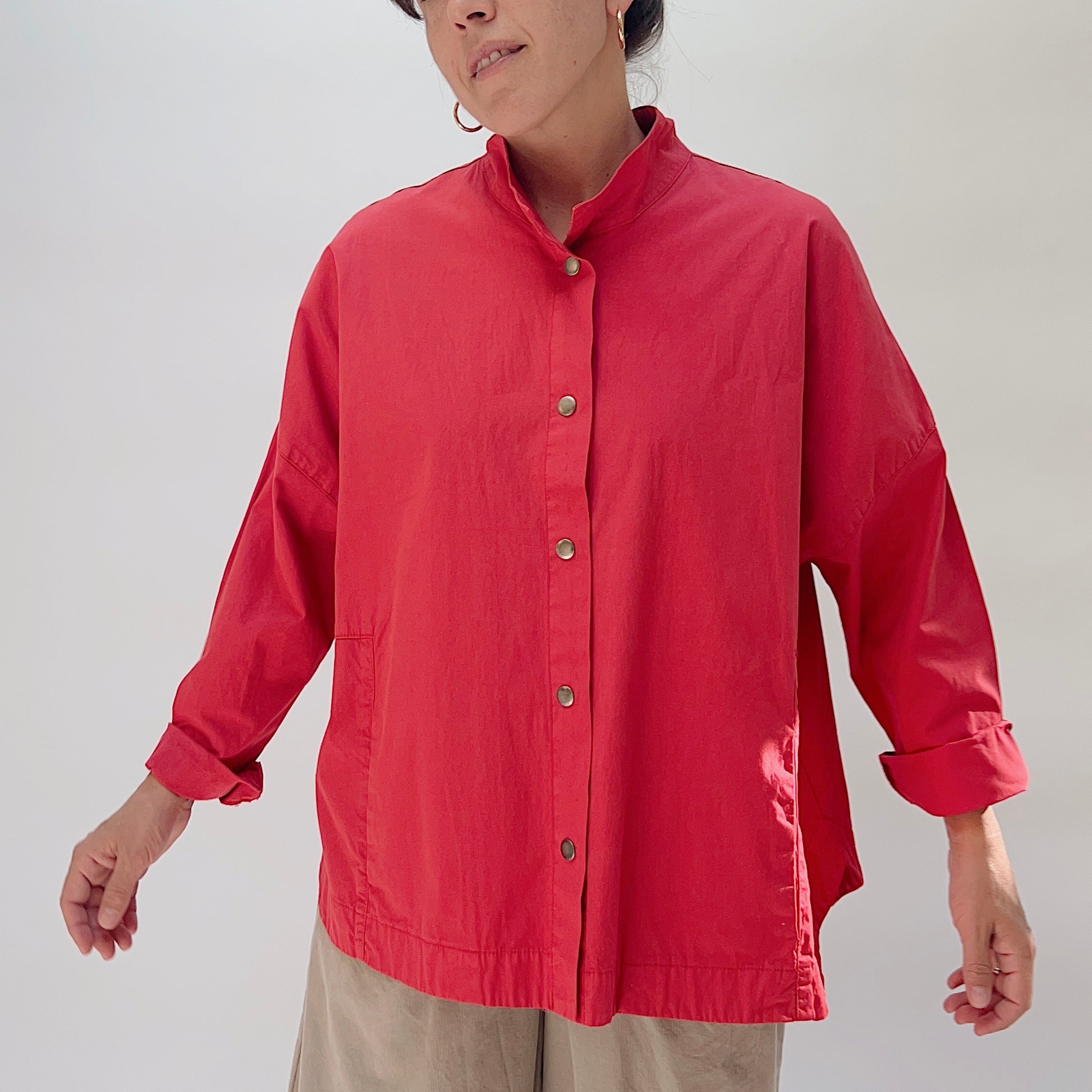 Eleven Stitch Stand Collar Jacket in Cayenne, front view on model, showing stand collar, five metal snap closures, two front patch pockets, and relaxed boxy silhouette, paired with khaki wide-leg trousers
