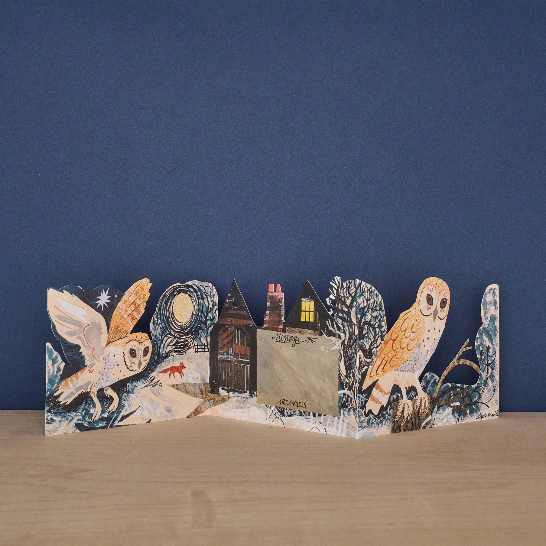 Three Fold Silent Flight concertina card open to reveal blank message panel beside a dark cottage door, with a barn owl in flight and a fox in the snow on one side and a perched owl among winter trees on the other, signed by Art Angels and Mark Hearld