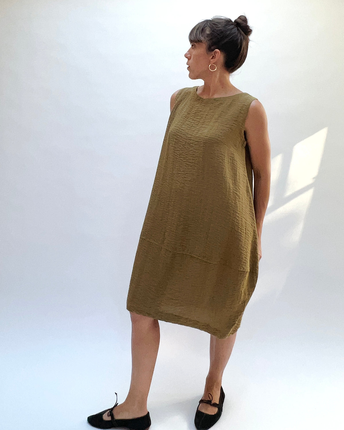 Eleven Stitch Travel Bubble Dress in Teak, angled front view showing the sleeveless design and crinkled fabric.
