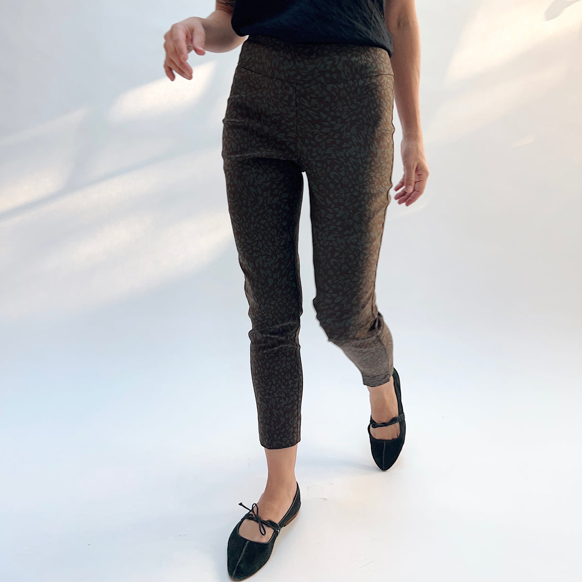 Lisette Sepia Leopard Slim Ankle Pant, front view in motion showing the slim ankle fit and sepia leopard print on a deep ground
