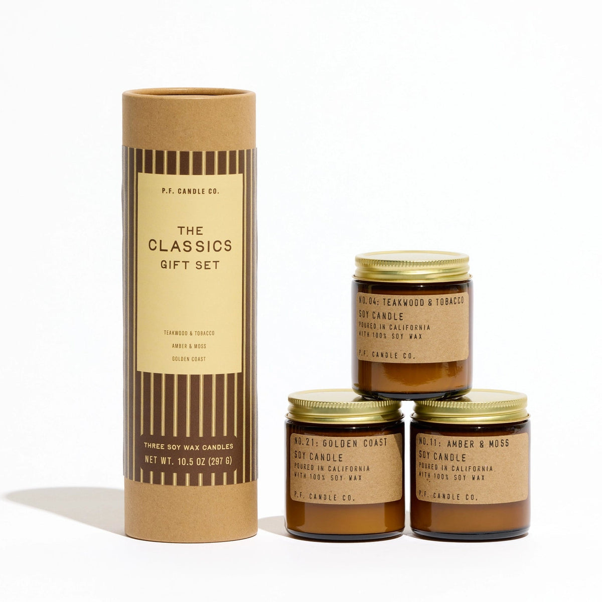The Classics striped kraft gift tube beside three amber glass mini candle jars with brass-colored lids.
