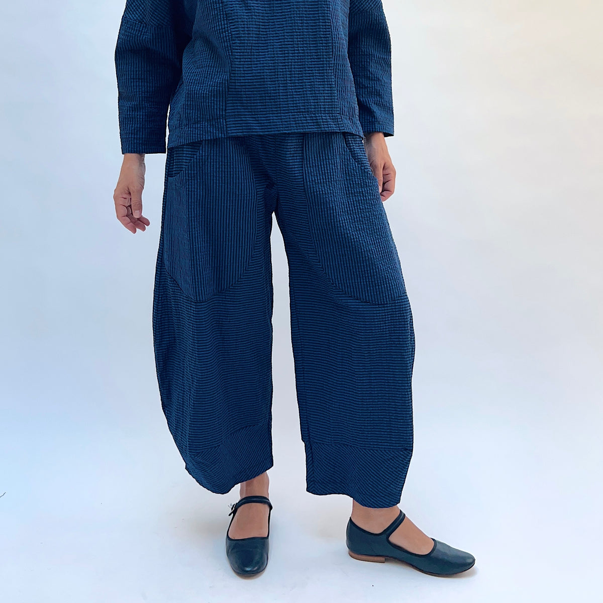 Niche Izzie Pant in Blue Seersucker Stripe, front view showing the wide-leg silhouette in teal and black seersucker stripe with front pockets
