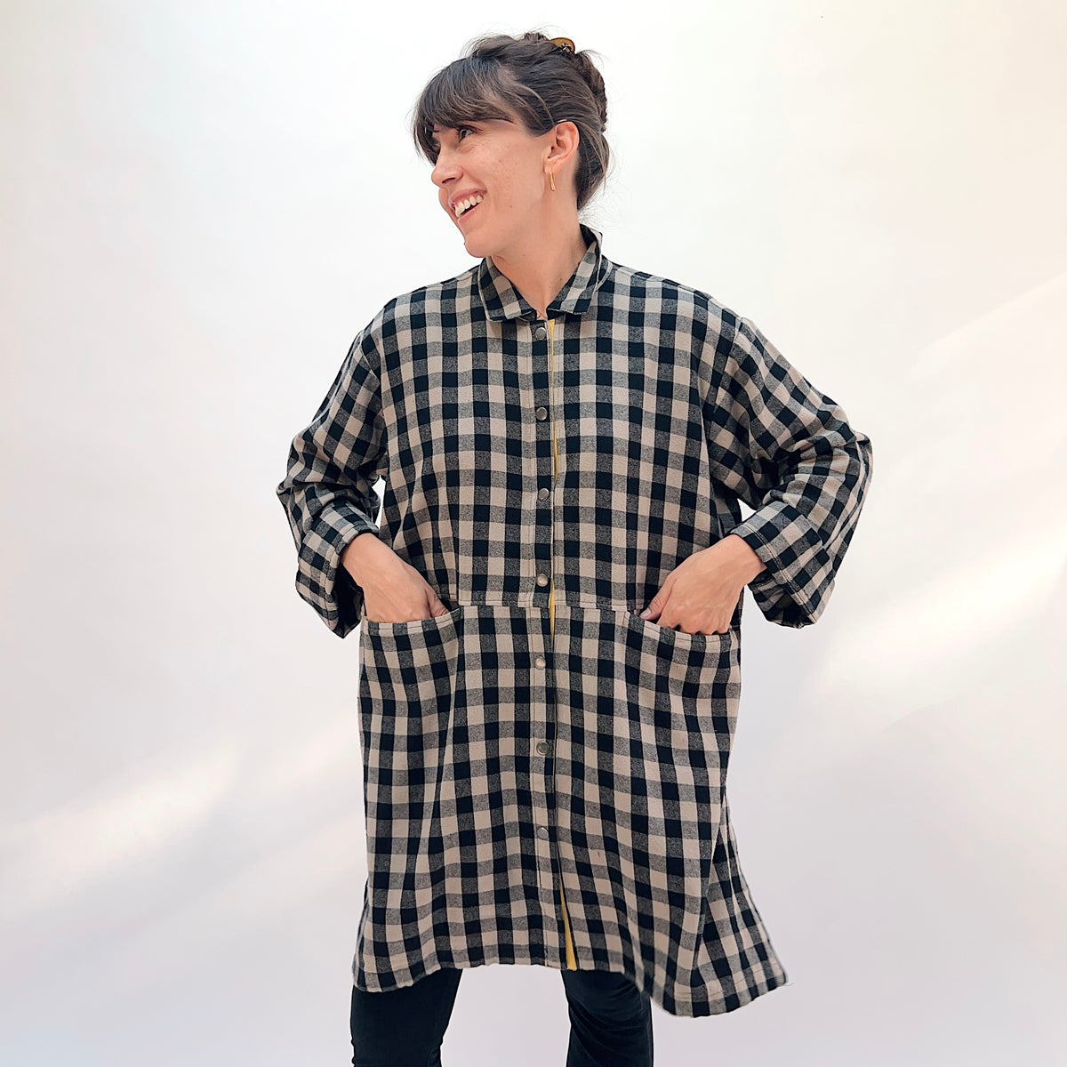Eleven Stitch Duster in Fennel, front view showing the knee-length oversized silhouette in black and natural gingham check flannel with mustard contrast side snap vent
