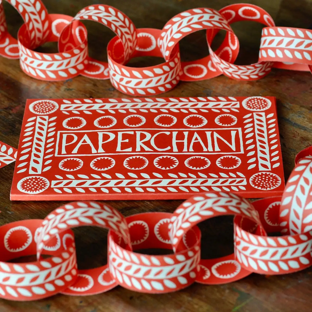 Red and white paper chain with 'Paperchain' packaging on a wooden surface
