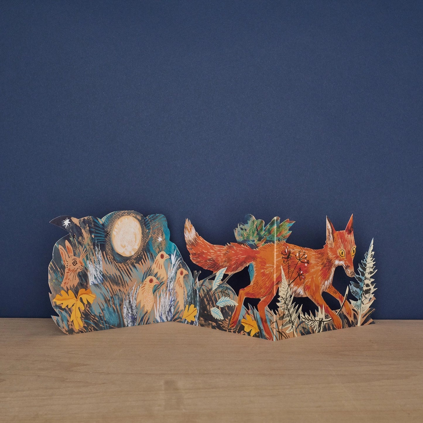 Hares Collage concertina card open to reveal blank message panel, with illustrated hares and meadow botanicals on either side, signed by Mark Hearld and Art Angels