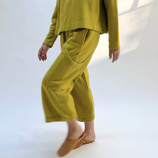 Angled view of Bryn Walker Pasha Fleece Pant in Chartreuse on a model, showing the cropped wide legs and large thigh patch pocket.
