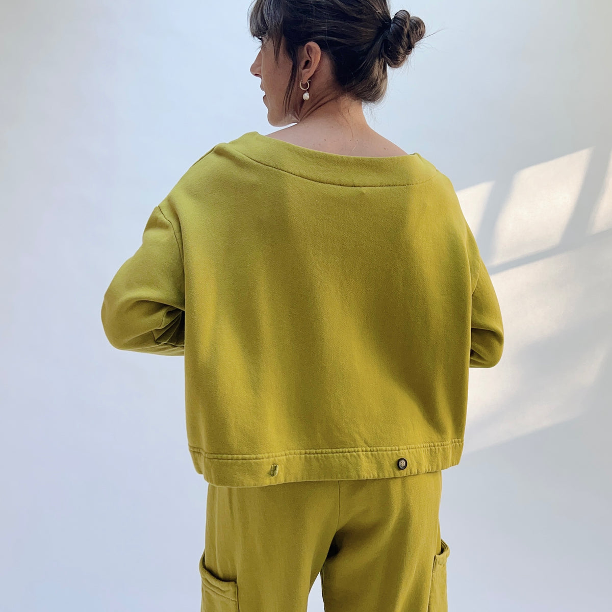 Back view of Button Back Fleece Pullover in Chartreuse, showing the loose silhouette and button detail along the lower hem.
