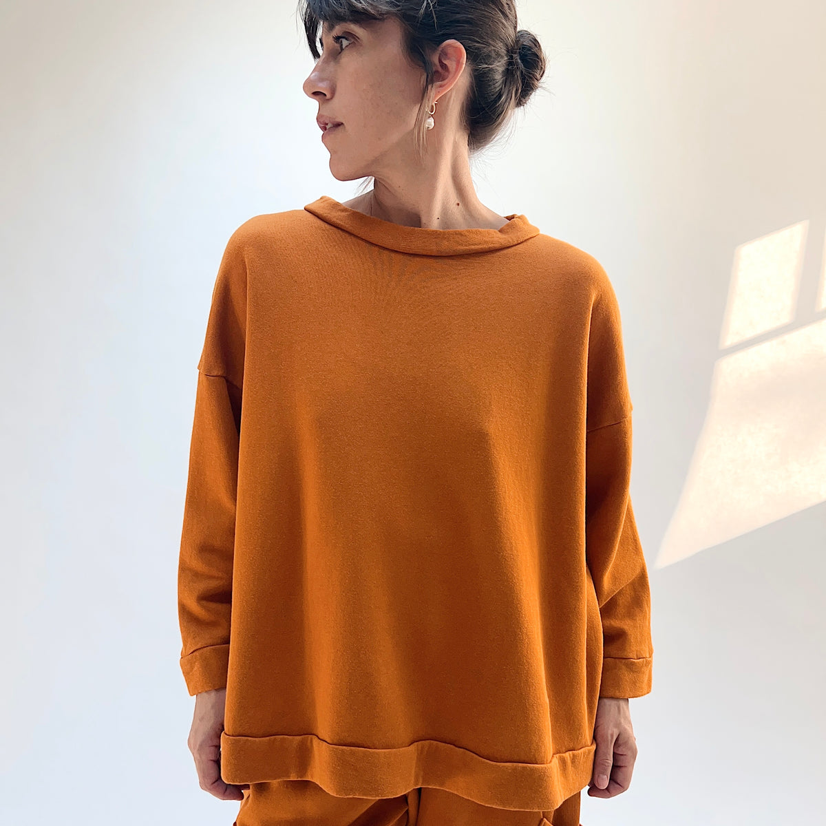 Front view of Bryn Walker Alden Fleece Sweatshirt in Yera on a model, showing the draped neckline, dropped shoulders, and banded hem.
