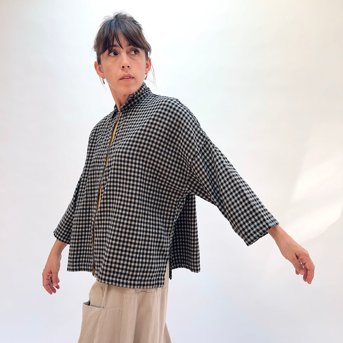 Eleven Stitch Small Check Big Shirt in Fennel, three-quarter side view showing the oversized boxy fit, stand collar, and mustard contrast placket in black and natural small gingham check
