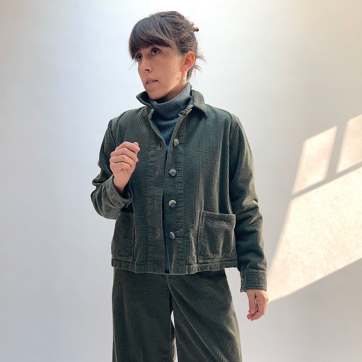 Front view of the Cut Loose Lux Corduroy Cropped Jacket in Kelp on a model, showing the collar, button front, and patch pockets.
