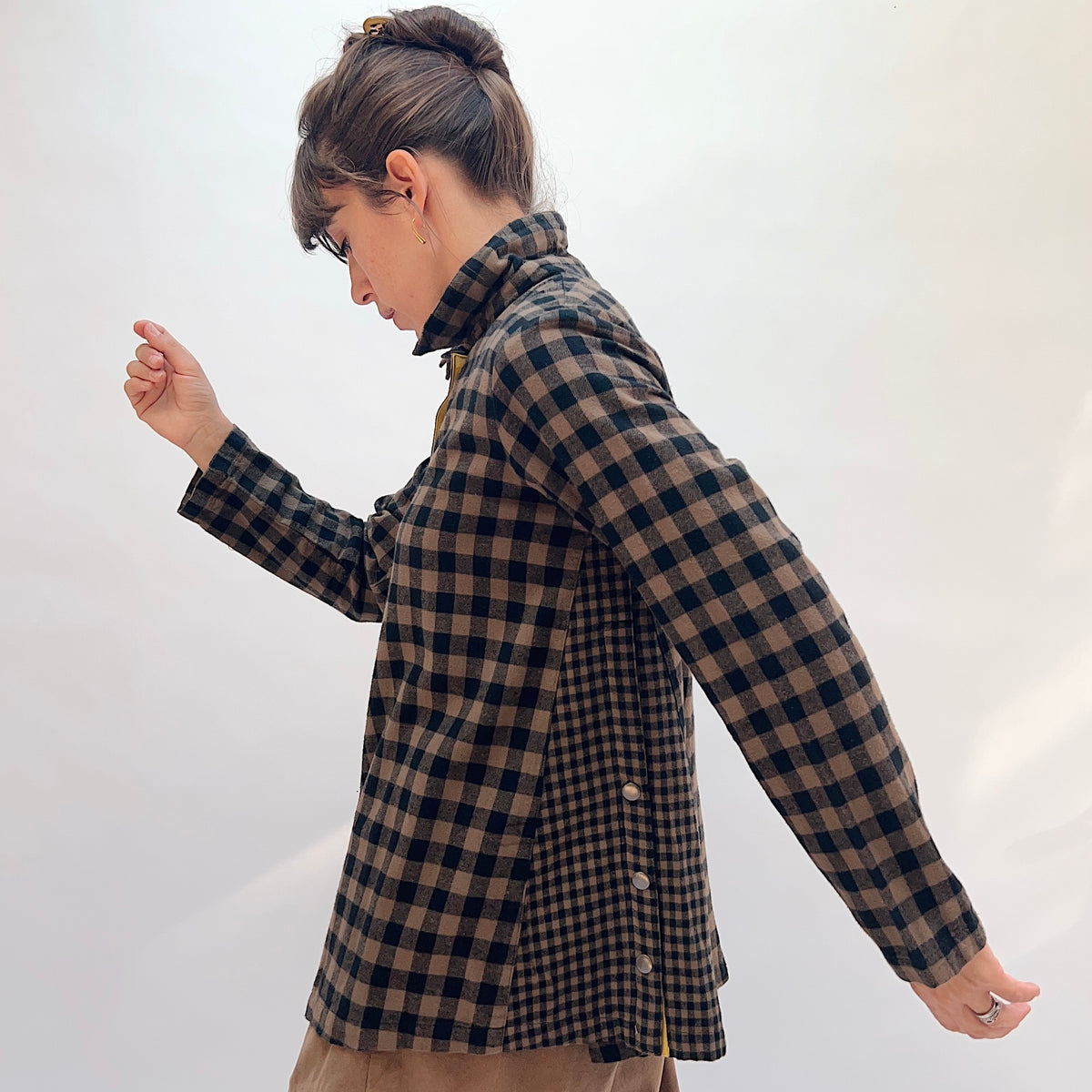 Eleven Stitch Placket Gusset Shirt in Winter Olive, side profile view showing the high funnel collar, snap gusset vent at the hem, and yellow contrast placket detail in brown and black gingham check
