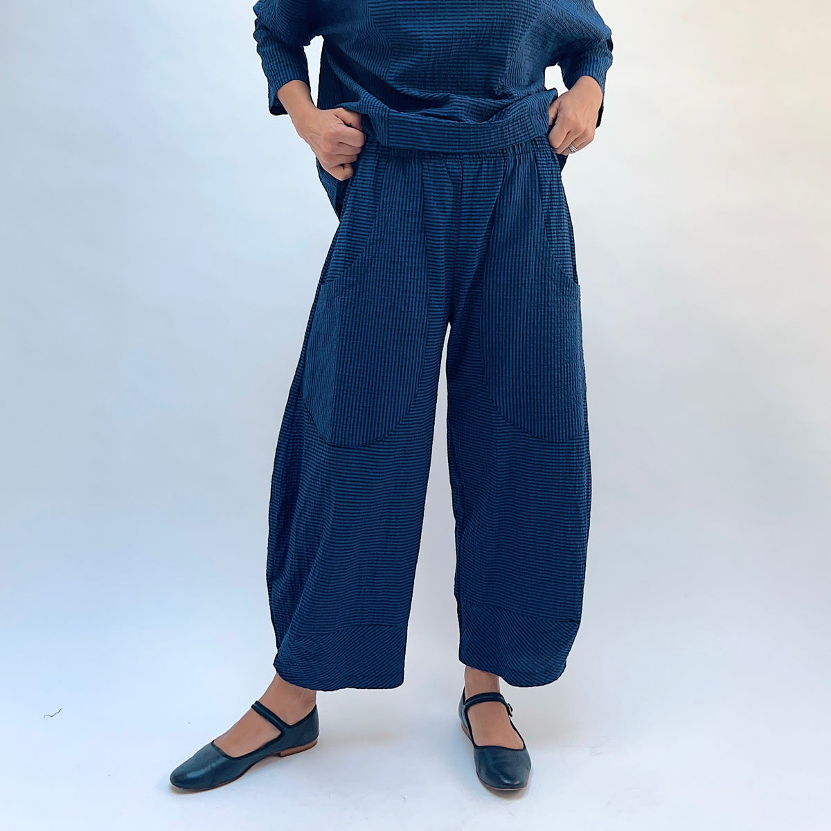 Niche Izzie Pant in Blue Seersucker Stripe, close front view showing the elastic waistband and front pockets in teal and black seersucker stripe
