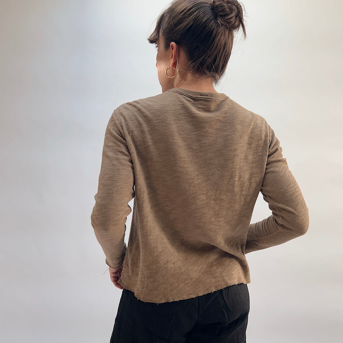 Model wearing the Cut Loose Snap Front Cardigan in Winter Olive, back view, showing relaxed silhouette and raw hem in warm olive tan cotton
