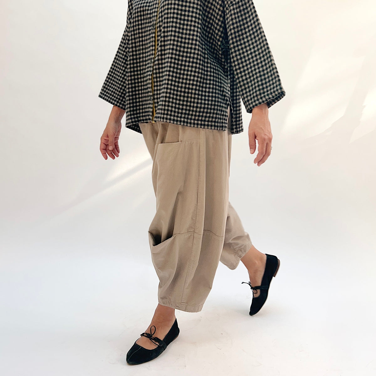 Eleven Stitch Corduroy Three Pocket Pant in Fennel, side view showing the balloon silhouette and hip patch pocket, styled with a gingham check shirt and black ballet flats
