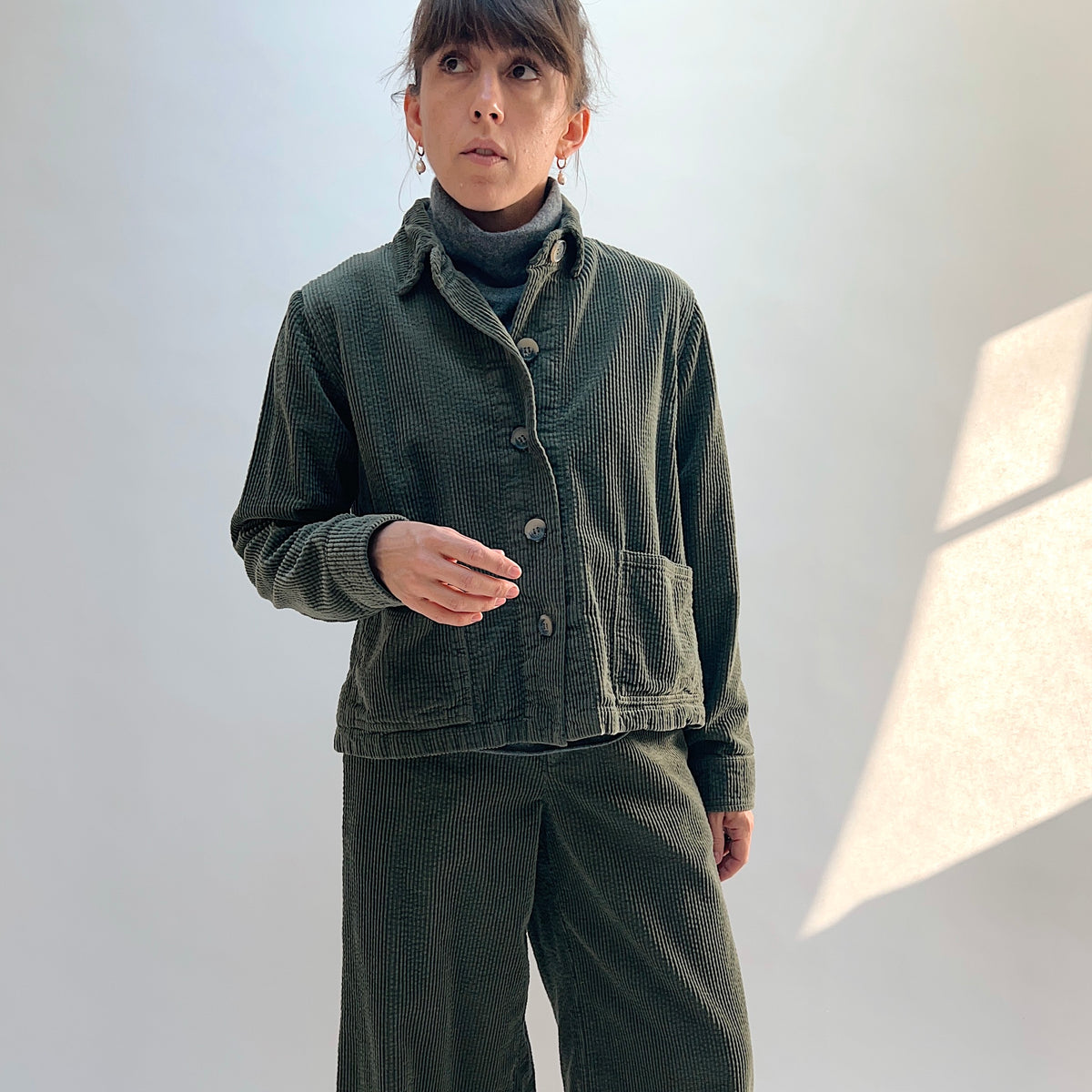 Model wearing the Lux Corduroy Cropped Jacket in Kelp with matching pants, showing the front buttons and two patch pockets.
