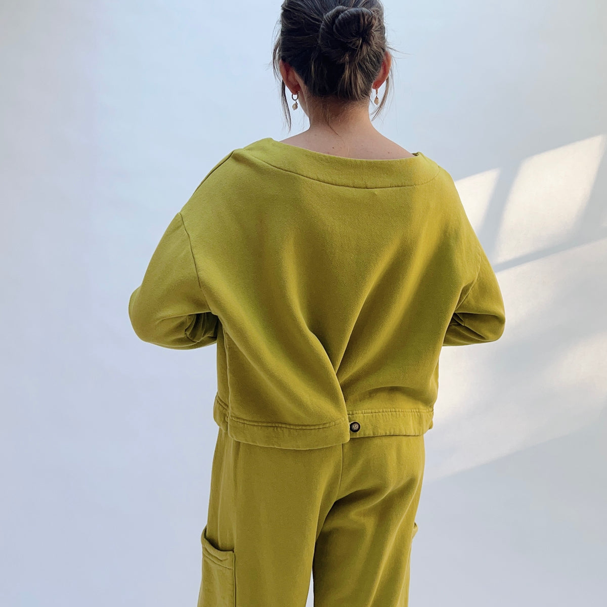Back view of Button Back Fleece Pullover in Chartreuse with the lower hem buttoned to create an overlapping drape.
