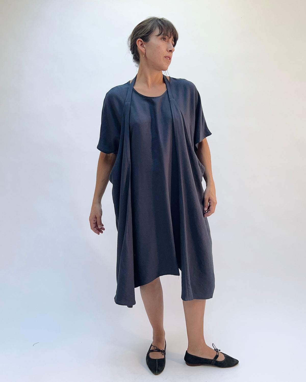 Niche Origami Dress in Carbon, front view showing the open one-shoulder drape styling with flowy fabric in dark carbon rayon
