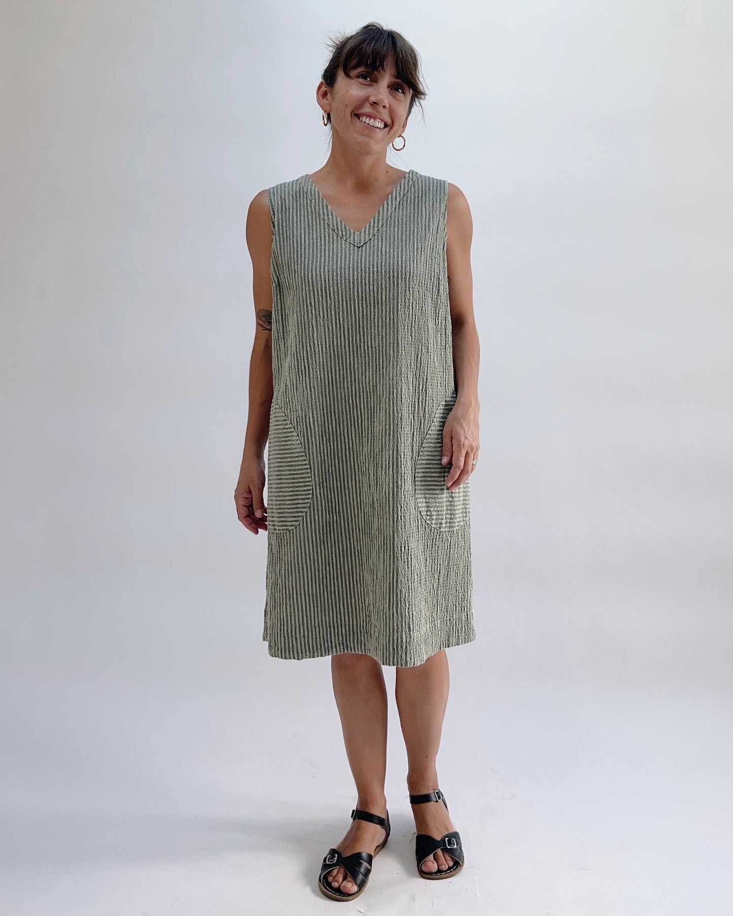 Cut Loose V-Neck Shift Dress in Balsam Green Stripe, full front view on model, showing v-neckline, two front patch pockets, and knee-length hem, worn with black sandals
