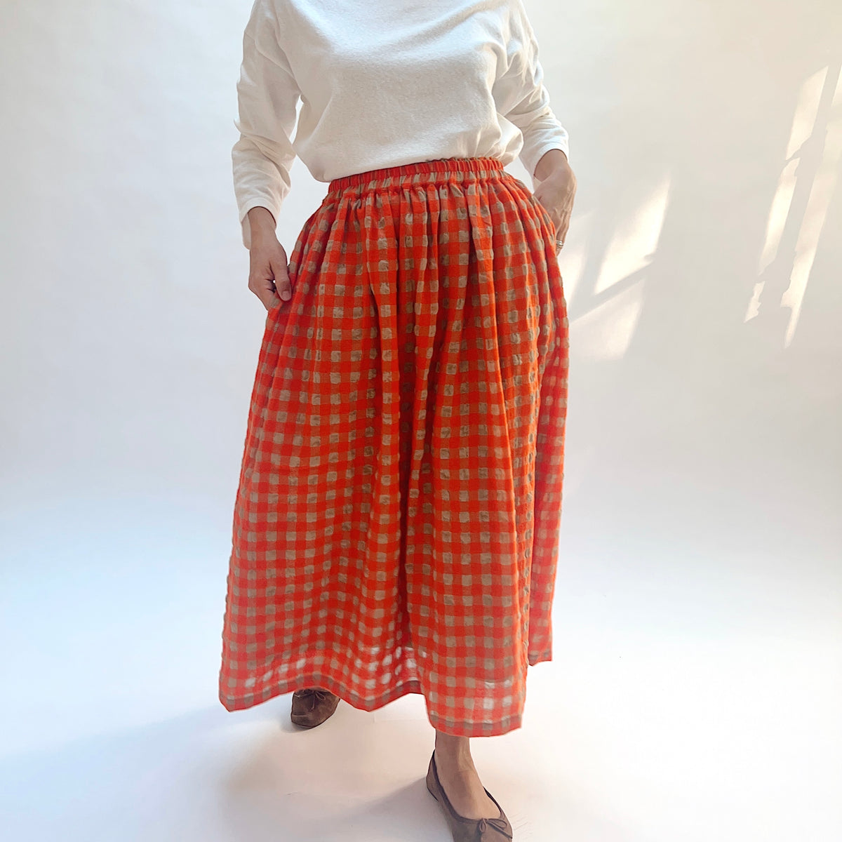 Ichi Antiquités Gingham Wool Check Skirt in Beige & Orange, front view with model holding one side of the skirt.
