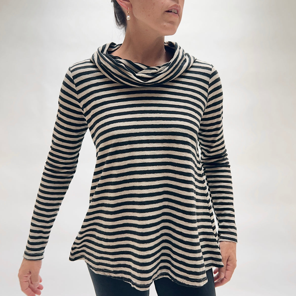 Model wearing the Cut Loose Striped Cowl Neck Pullover in Moonbeam from the front, showing the generous draped cowl neckline, long sleeves, and relaxed A-line silhouette in moonbeam and black horizontal stripe cotton-linen blend, with a curved hem and side slits
