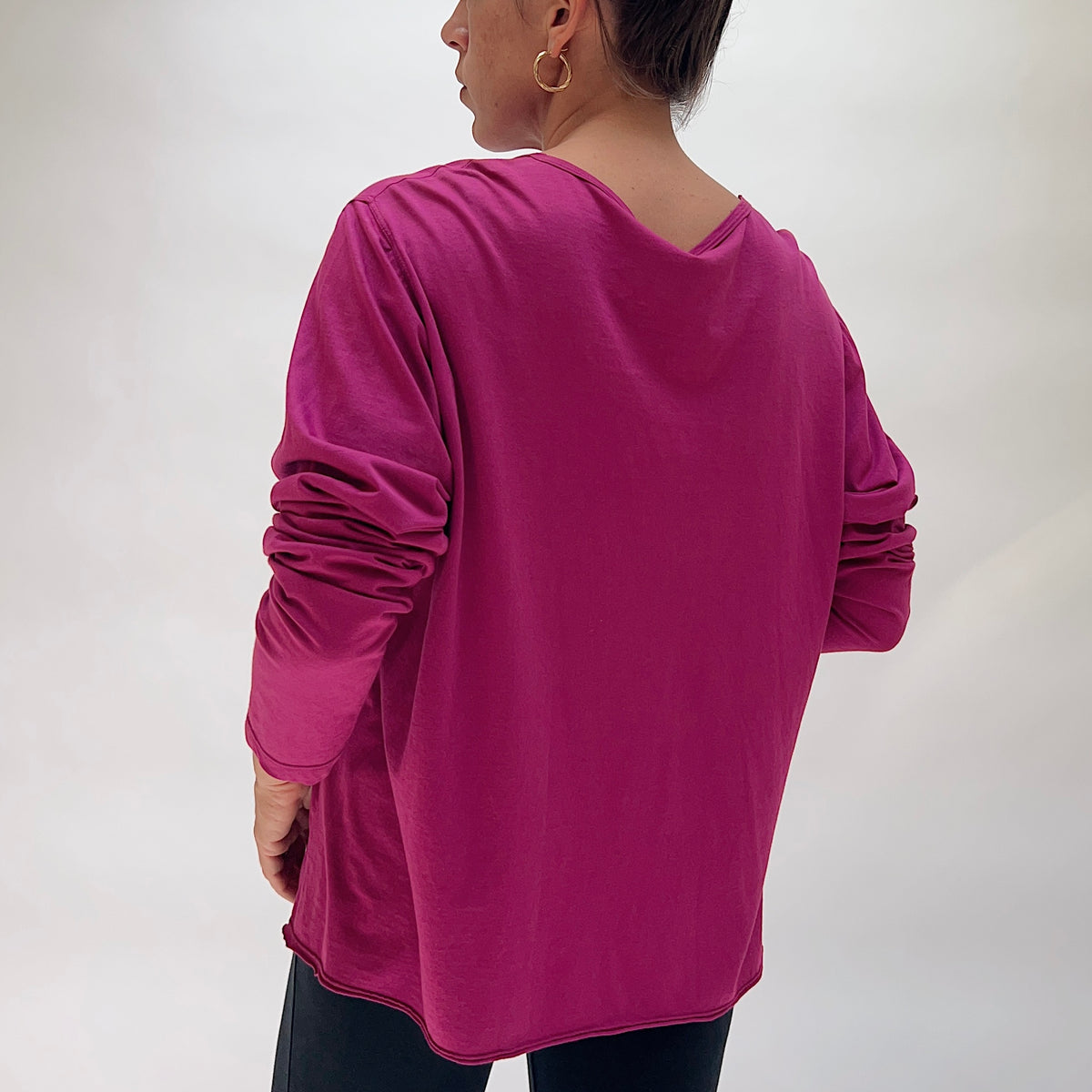 Back view of the North Star Base Tissue Cotton Long Sleeve Agnes Tee in Raspberry, showing the relaxed boxy fit, long sleeves, and curved lettuce-edge hem in rich magenta raspberry tissue cotton
