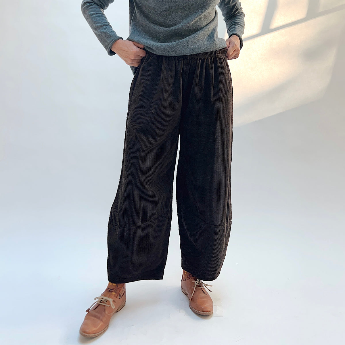 Front view of Cut Loose Lux Corduroy Lantern Pant in Chocolate on a model, showing the gathered waistband, corduroy texture, and rounded legs.
