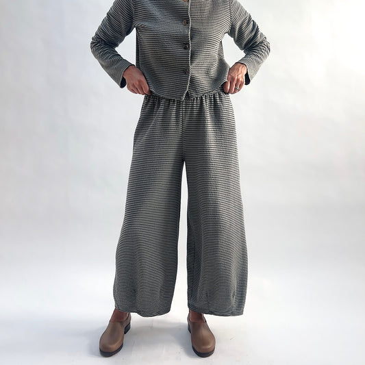 Front view of model wearing squirrel and black fine horizontal stripe wide-leg cropped pants with elastic waist and dart shaping, styled with the matching striped cropped cardigan and taupe slip-on shoes against a white background.
