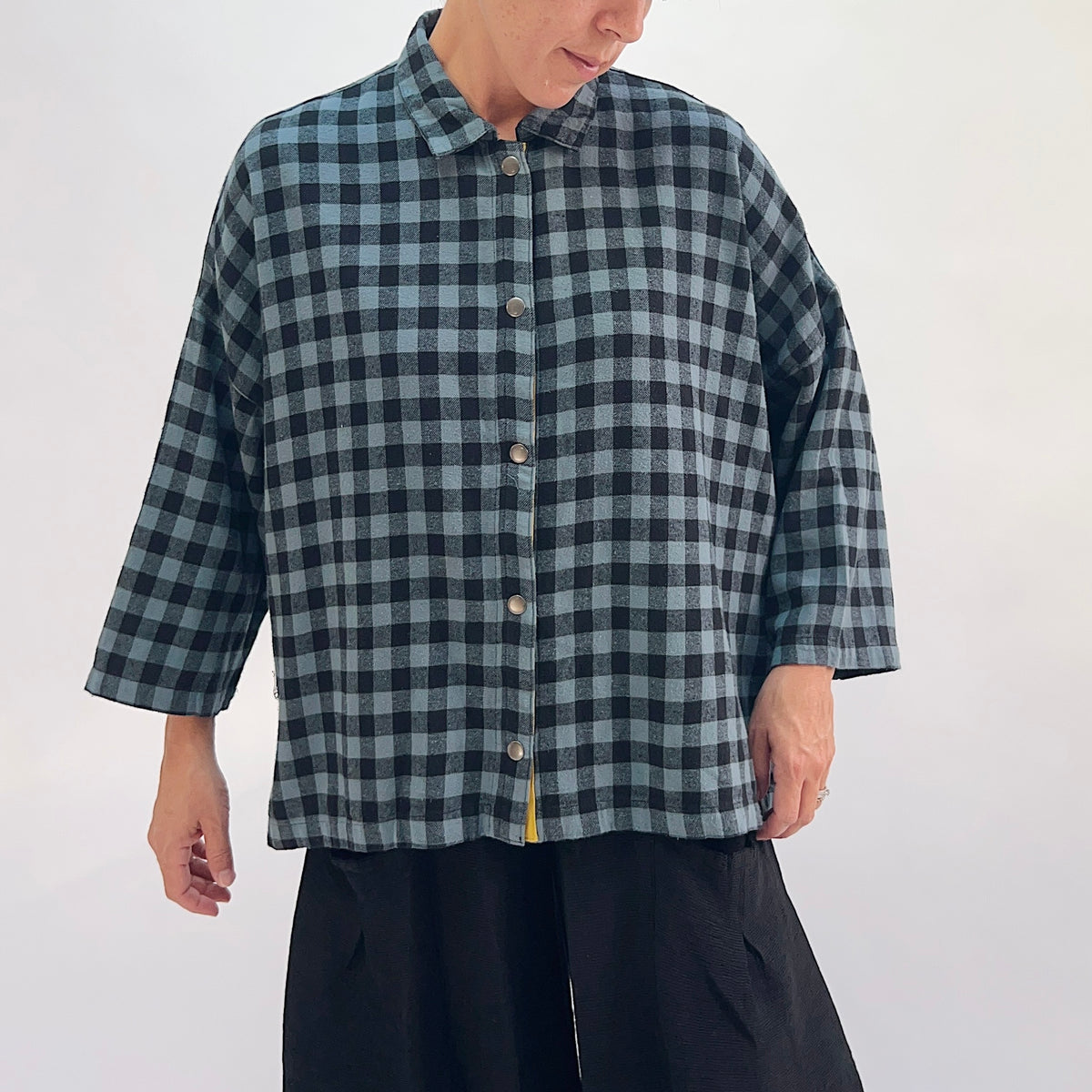 Eleven Stitch Big Check Big Shirt in Dusty Denim, full front view showing the boxy hip-length silhouette, point collar, and mustard contrast side vents in dusty blue and black gingham check flannel
