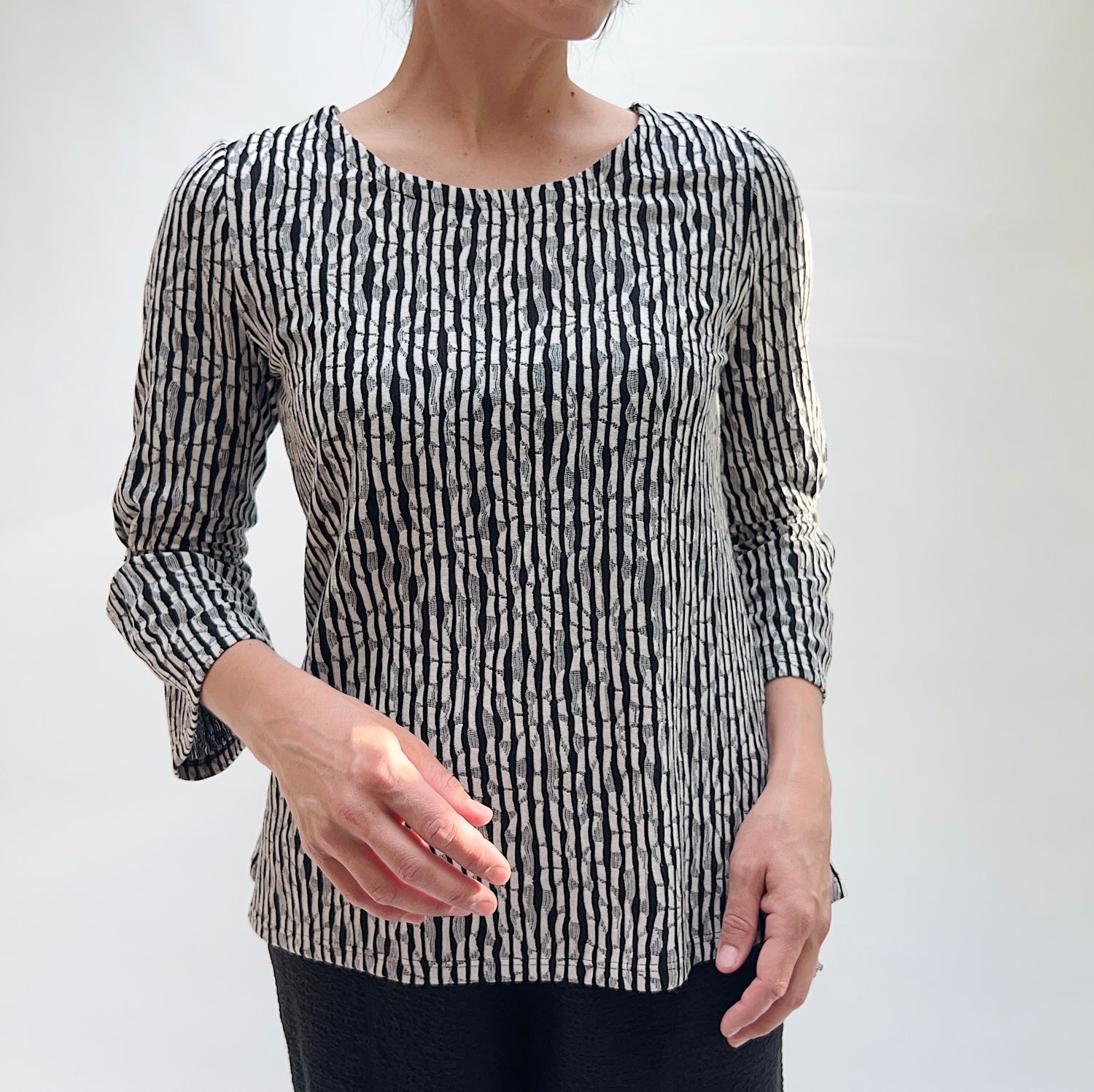 Person wearing a black and white patterned top against a plain background