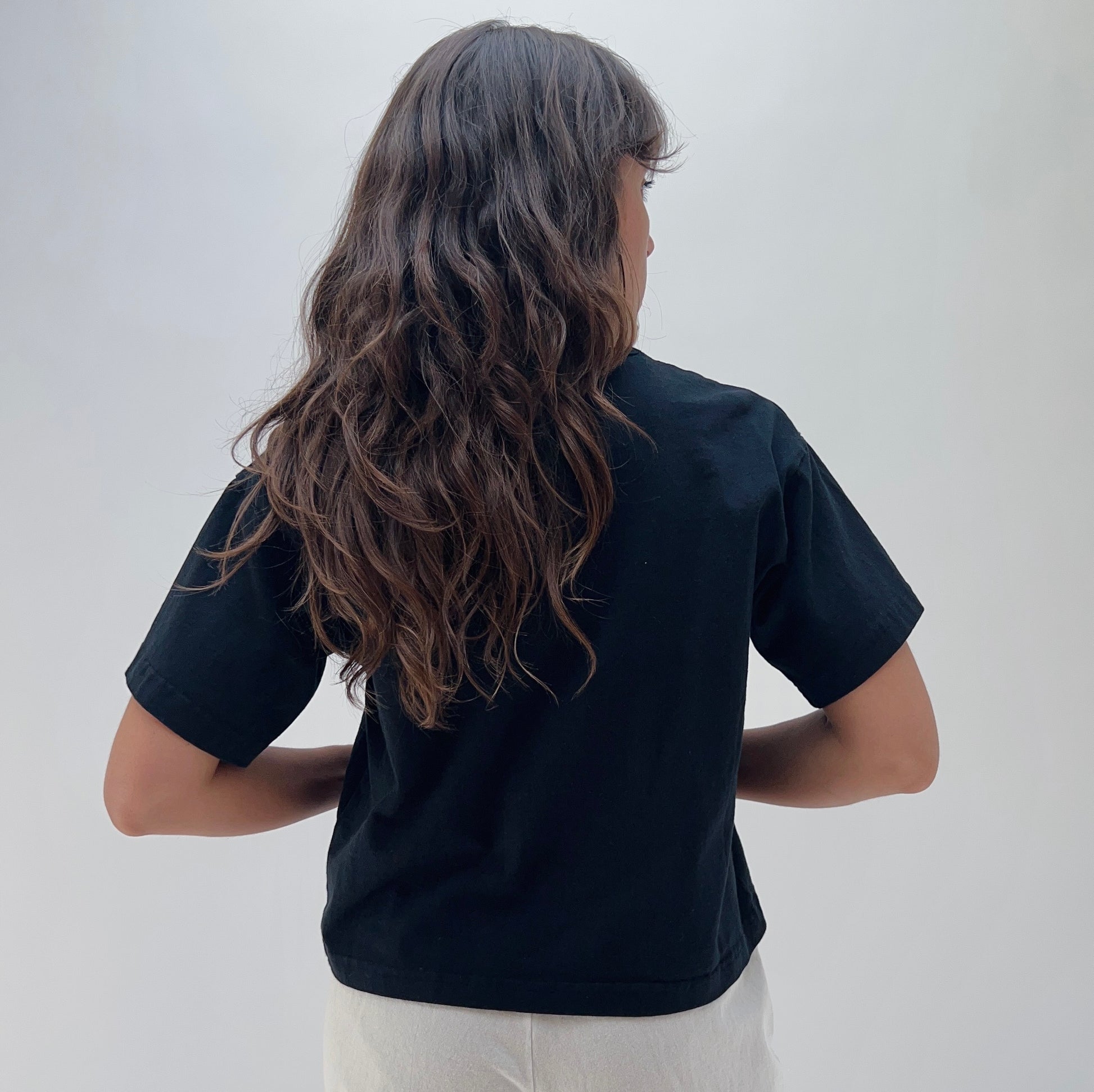 A person wearing a black crop crew t-shirt made of cotton.