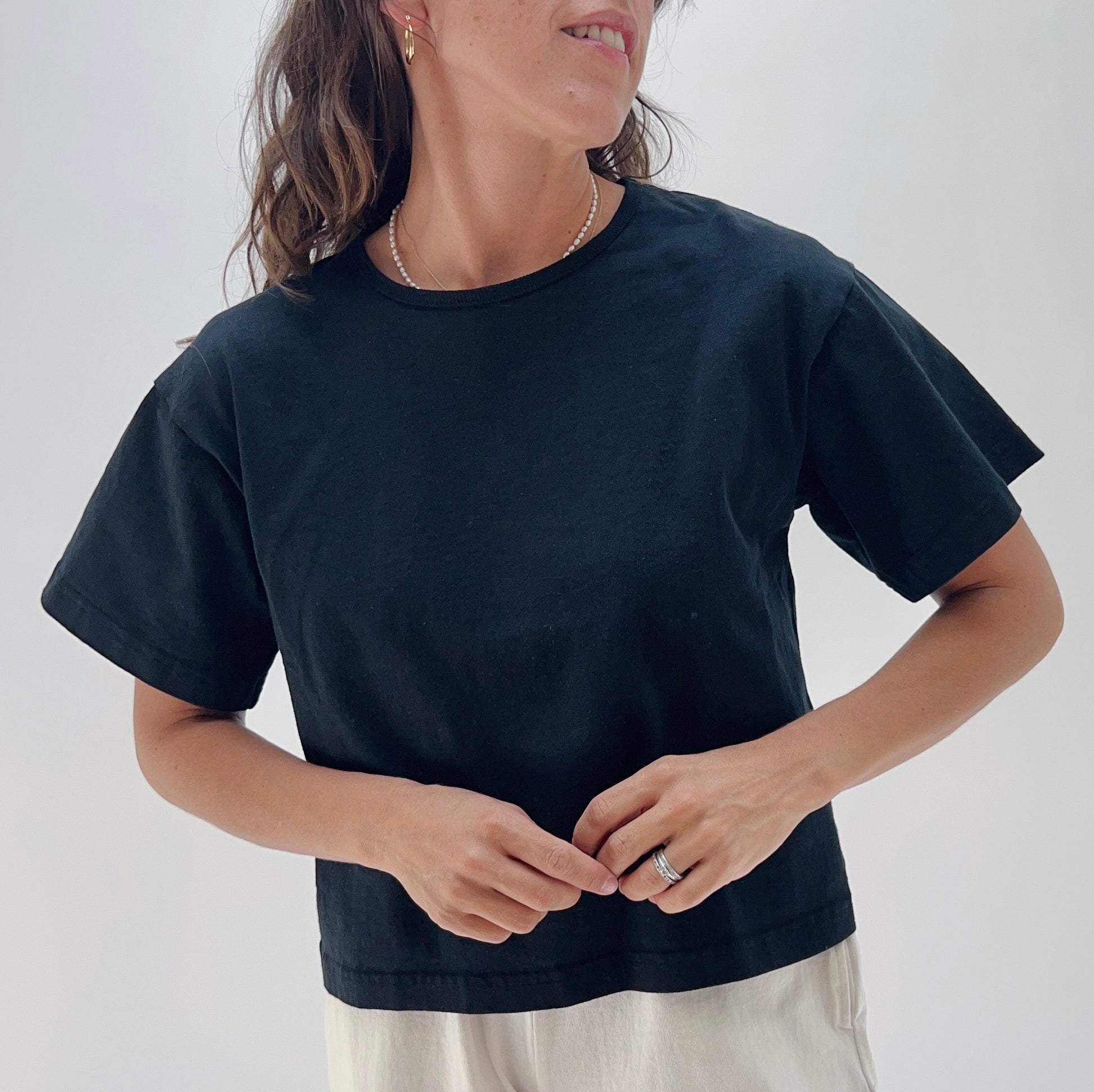 A person wearing a black crop crew t-shirt made of cotton.