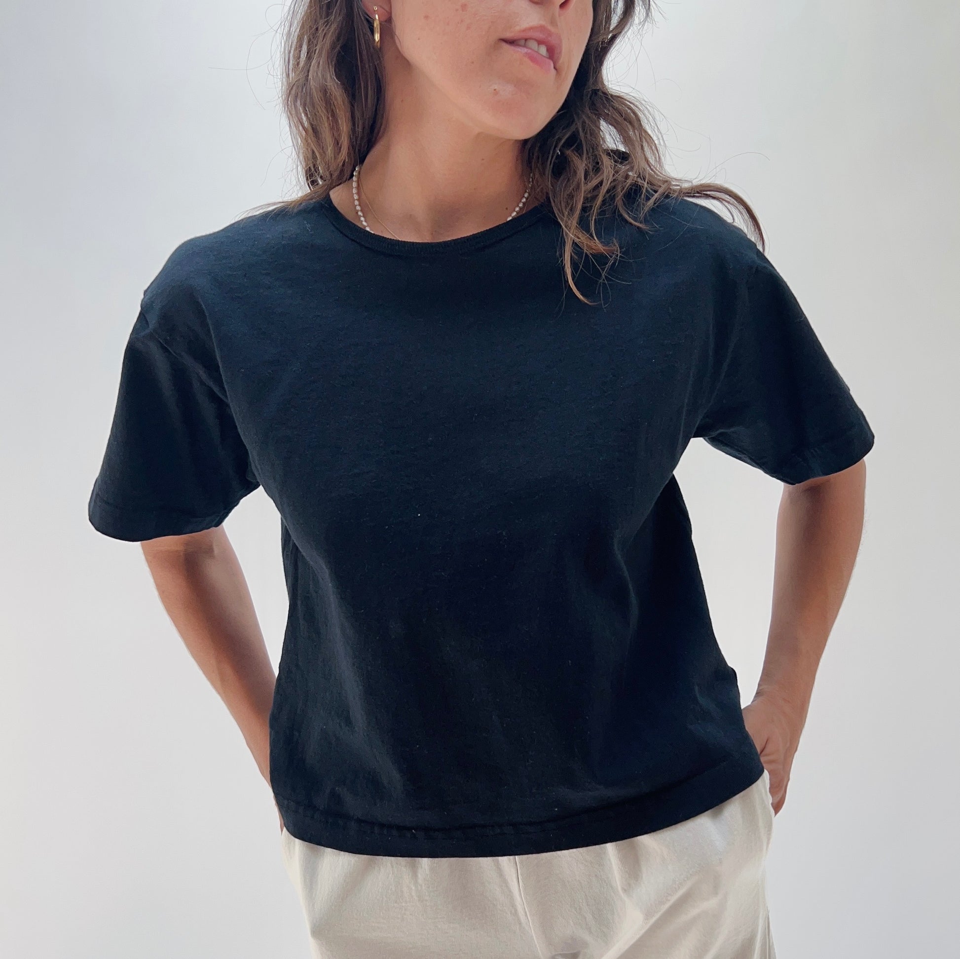 A person wearing a black crop crew t-shirt made of cotton.