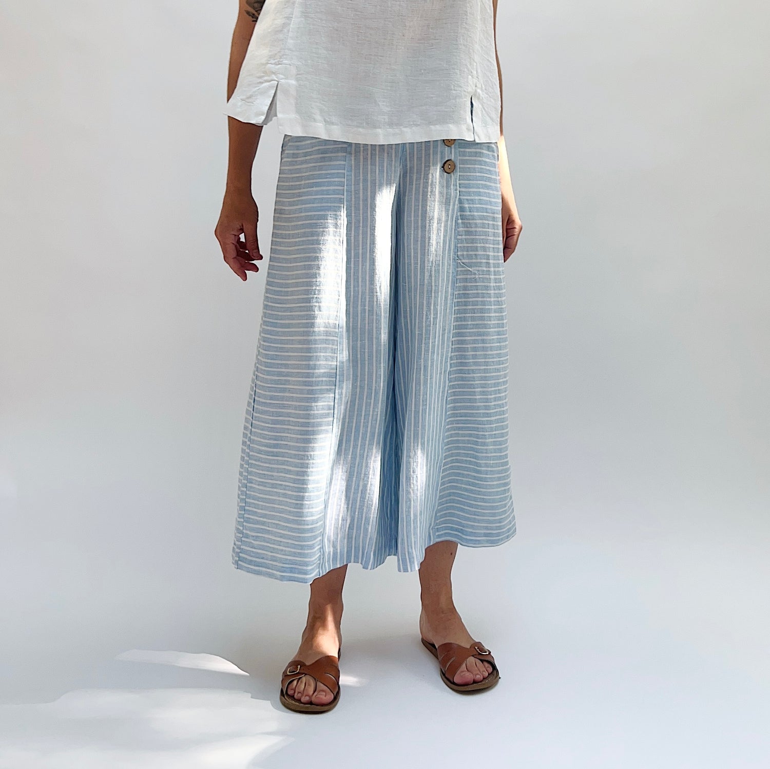Person wearing light blue striped pants and white top on a plain background