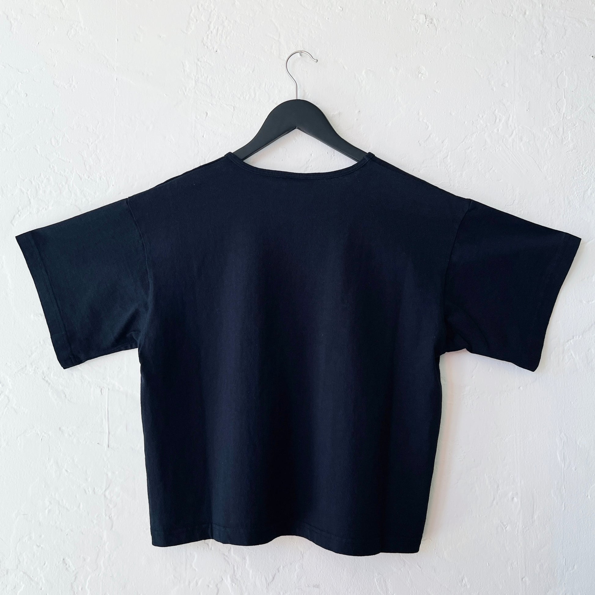 Black crop top on a hanger against a white wall