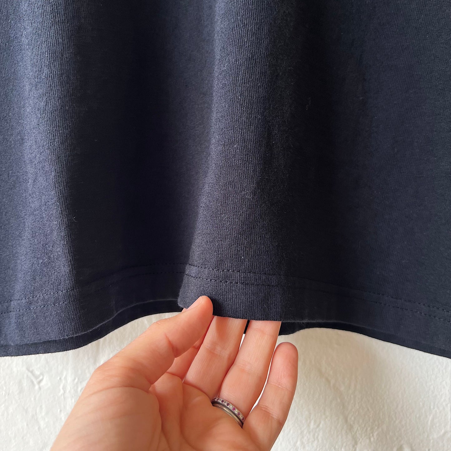 Close-up of a hand holding the hem of a black t-shirt