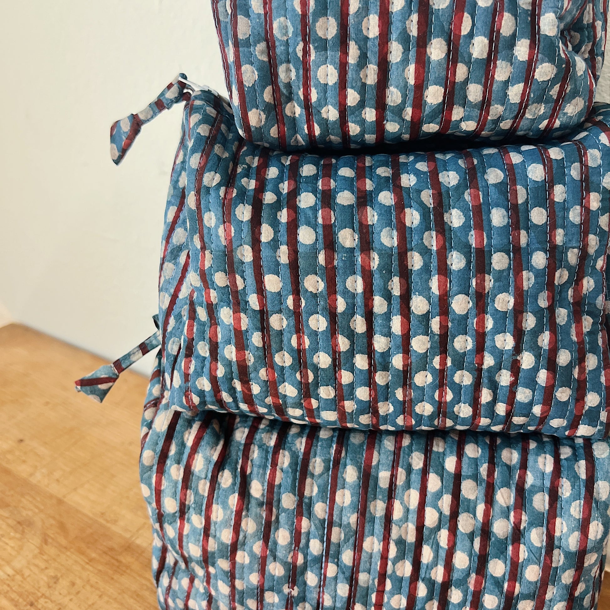 Close-up of the Toiletry Bag in Persephone Blockprint showing the slate blue quilted cotton with burgundy stripe and white polka dot block-print motif and vertical quilting stitches