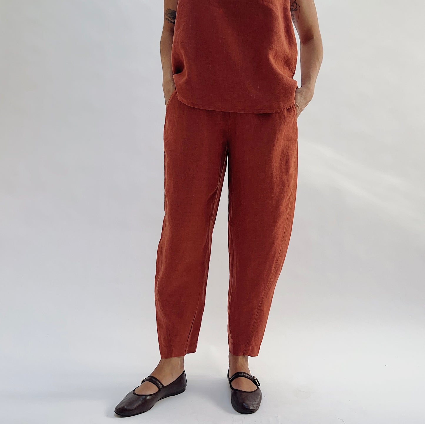 Close-up front view of the Seamed Taper Pant in Terracotta by Yuvita, highlighting the seamed front leg, relaxed linen drape, and tapered fit, styled with a matching terracotta linen tank
