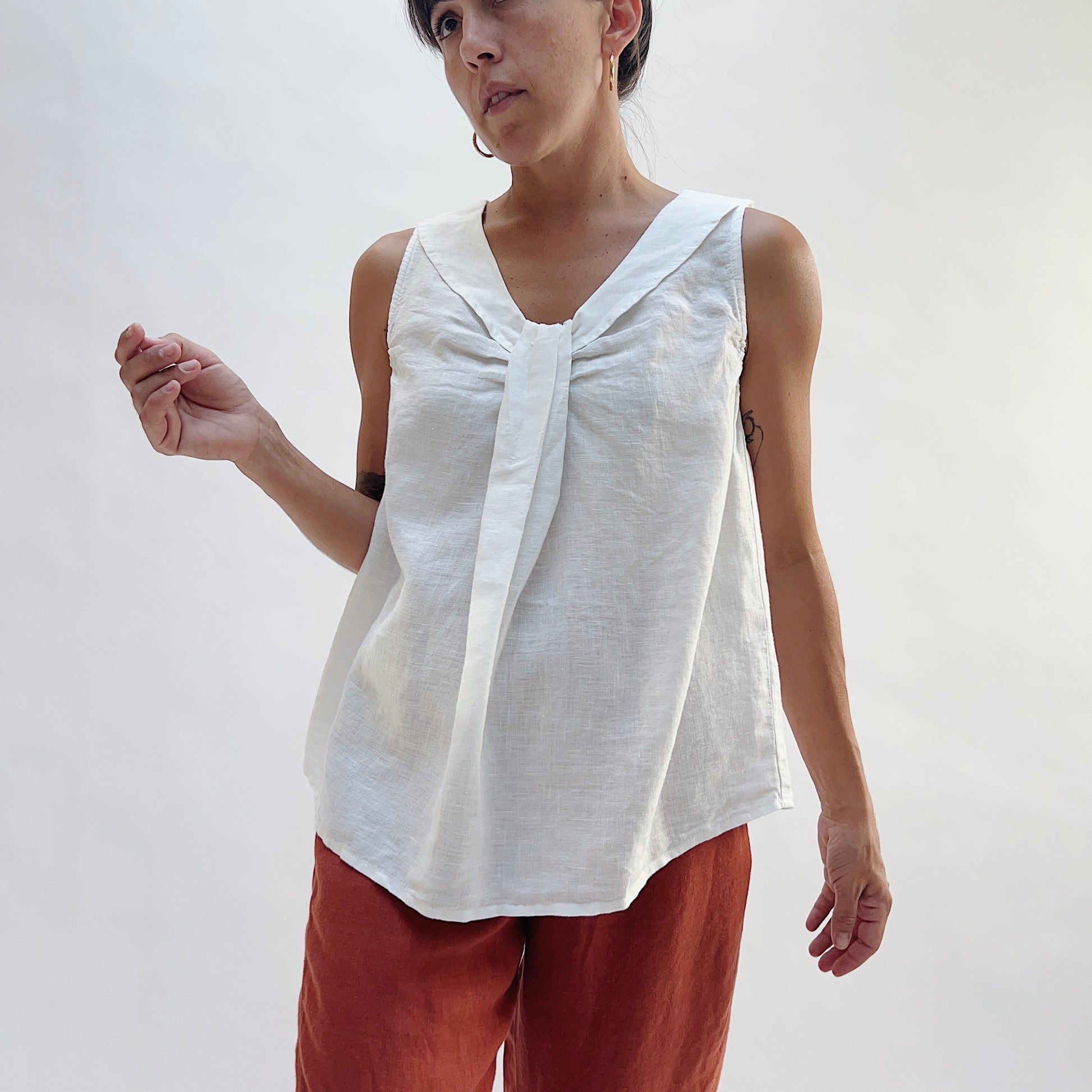 Front view of the Sailor Tank in White by Yuvita, showing the V-neckline with gathered twist detail, sailor collar, and relaxed linen silhouette in white, styled with terracotta linen wide-leg pants