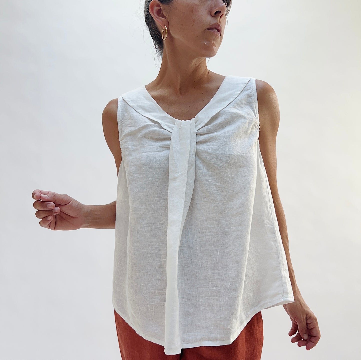 Close-up front view of the Sailor Tank in White by Yuvita, highlighting the gathered twist neckline, sailor collar, and relaxed A-line drape in white linen, styled with terracotta linen pants